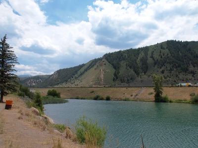 [An oversized pond sitting beside the interstate with green mountains in the background.]